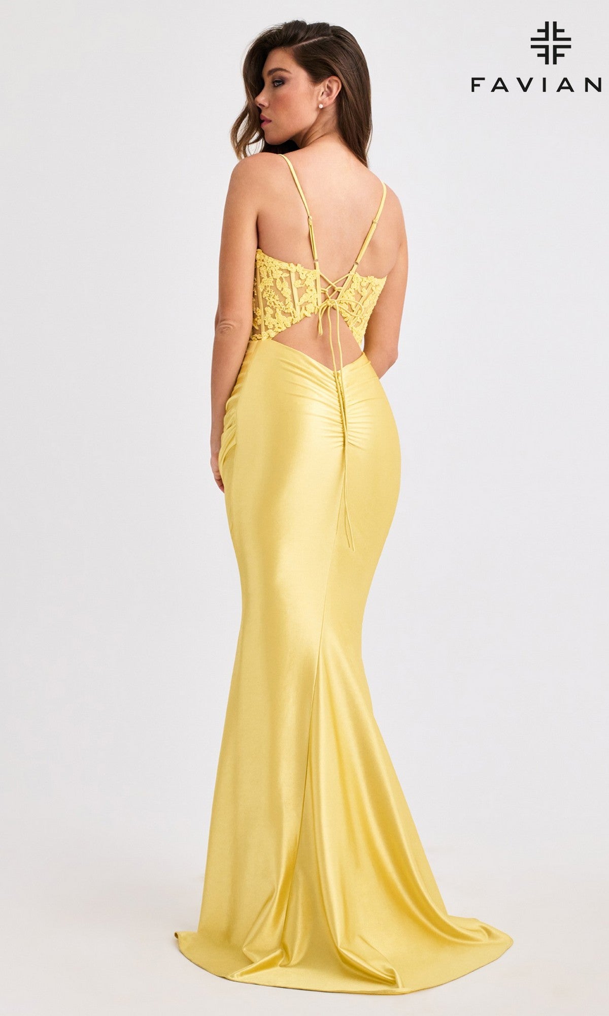 A woman wearing the Faviana 11400 long prom dress in yellow satin, featuring a lace corset bodice and lace-up back, stands against a plain background with the